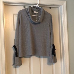 Grey sweater with cowl neck and trumpet sleeves.